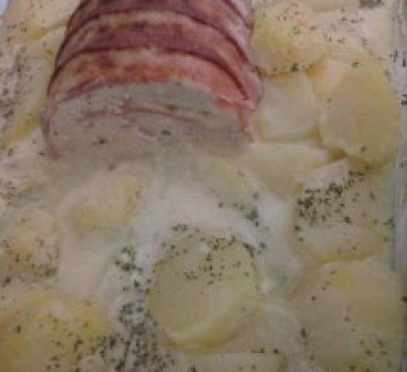 Rollo de carne con beicon, con guarnición de patatas y salsa de cebolla.